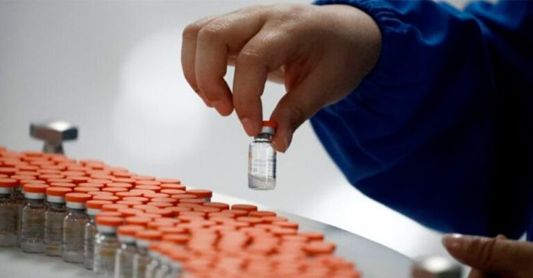 Mulher em laboratório manipulando ampolas das vacinas contra a Covid-19